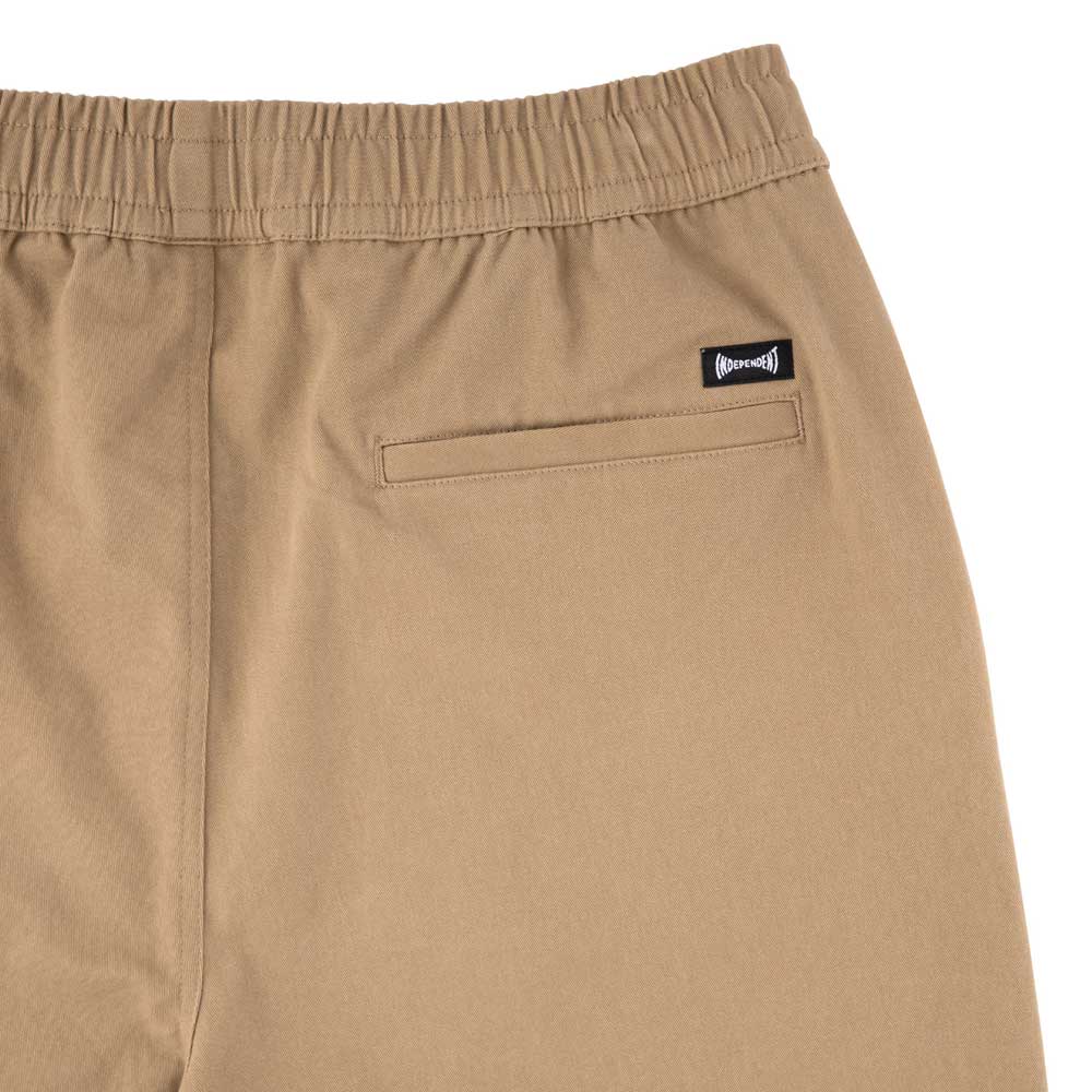 Close-up of the back of Span Elastic Waist Shorts Khaki Bottom Mens Independent, showing a baggy fit, long inseam, elastic waistband, single welt pocket, and a small black and white logo tag above the pocket.