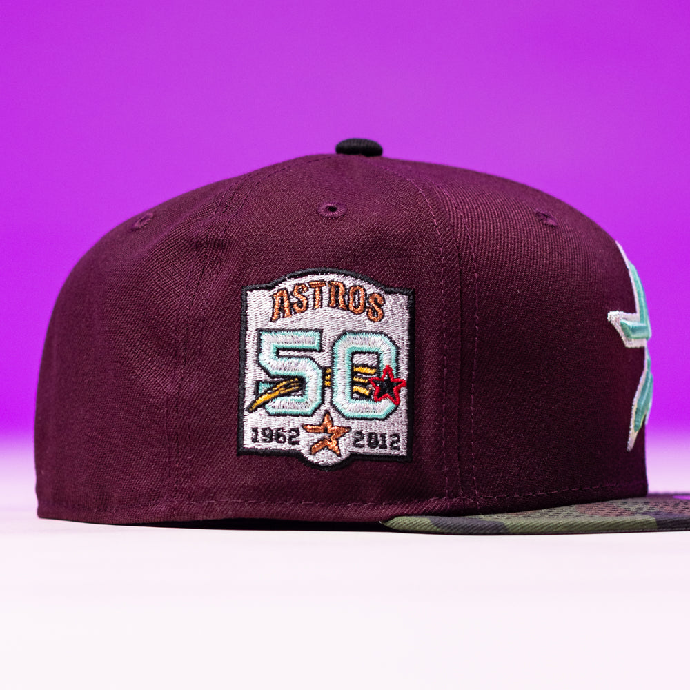 The Swag Era 50th Camo Maroon Houston Astros New Era Hat 5950 Fitted is a maroon cap with a vibrant embroidered patch honoring the team’s 50th anniversary (1962–2012), displayed on a purple background.