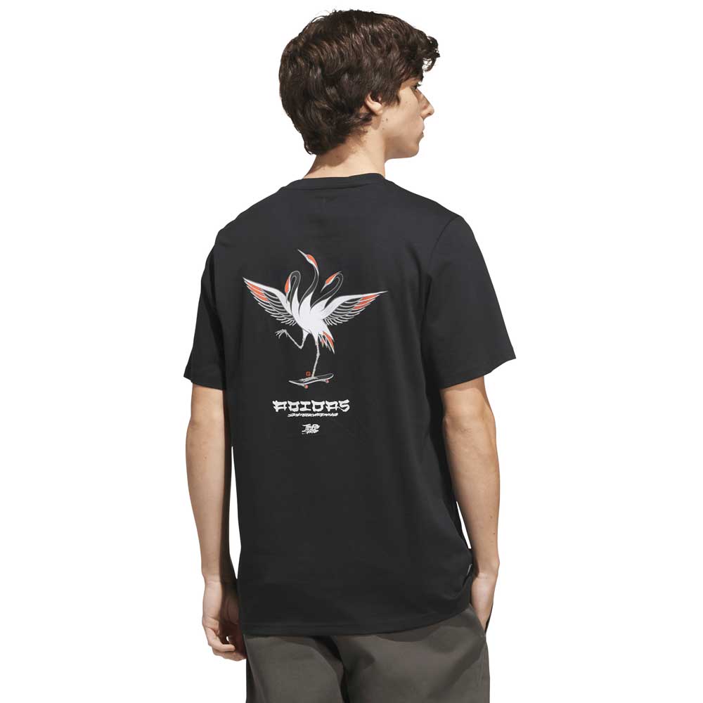 A person wearing the Adidas Skateboarding TOS Crane Tee Black White KS4336, which features a crane graphic and stylized “Temple of Skate” text on the back, standing and facing away from the camera.
