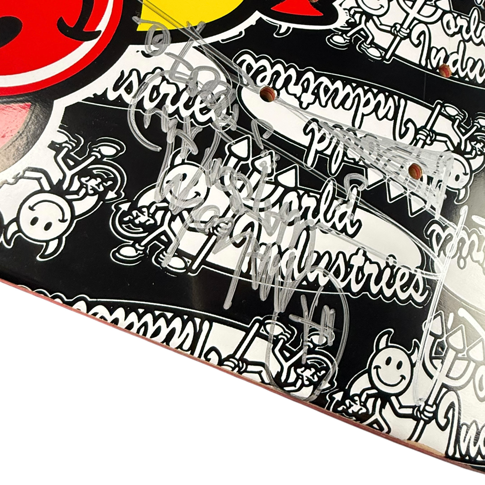 Close-up of a Team World Industries Skateboards Deck 7.75x31.2 Circa 2007, featuring black and white cartoon graphics and multiple silver marker autographs—a signed collectible.