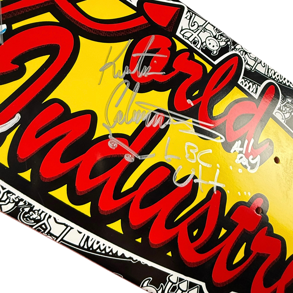 A close-up of the Team World Industries Skateboards Deck 7.75x31.2 Circa 2007, a signed collectible featuring bold yellow, red, and black graphics with white signatures and doodles including “LBC” and “All Day.”.