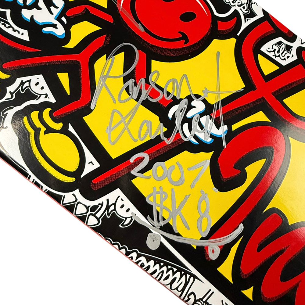 A close-up of the Team World Industries Skateboards Deck 7.75x31.2 Circa 2007 Signed Collectible, featuring bold red, yellow, and black graphics with a silver "Rosen Xauler 2007 $K8" autograph.
