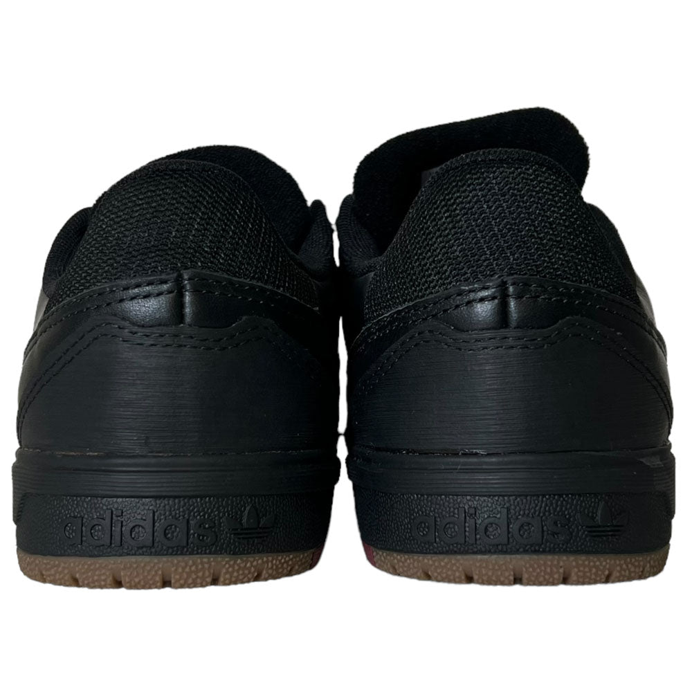 A pair of Tyshawn 2 II Adidas Skateboarding Core Black/Core Green leather shoes viewed from the back, featuring gum soles and embossed Adidas logos on the heels, blend style and durability for skaters.