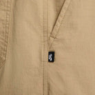 Close-up of FV7347297 Kearny Cargo Pant Khaki Nike SB Skate Dri Fit fabric with a diagonal seam and pocket, featuring a small black tag with white Nike SB logo, highlighting this classic cargo skate pant style.