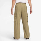 A person is seen from behind wearing FV7347297 Kearny Cargo Pant Khaki Nike SB Skate Dri Fit with side and back pockets, paired with a white shirt and black-and-white sneakers for a casual look.