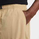 A close-up of a person wearing FV7347297 Kearny Cargo Pant Khaki Nike SB Skate Dri Fit with their right hand in the pocket and a black shirt partially visible at the waist.