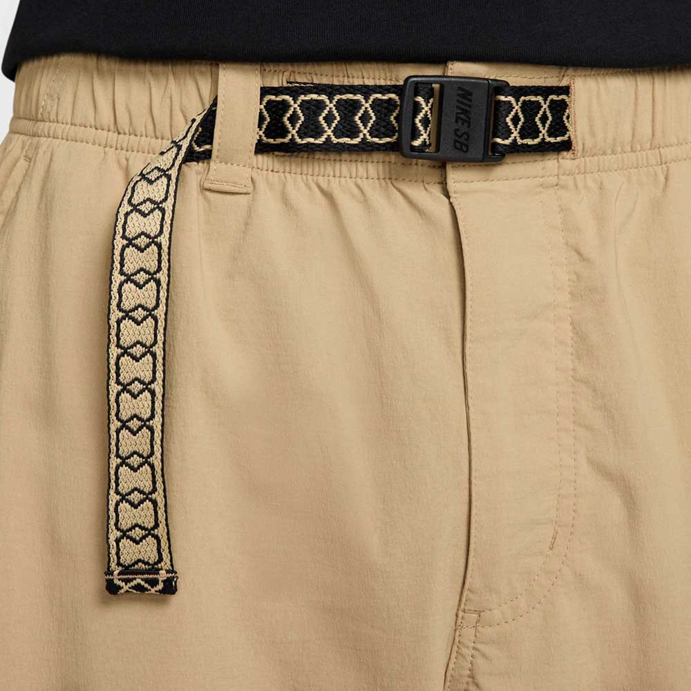 Close-up of the FV7347297 Kearny Cargo Pant Khaki by Nike SB, featuring an elastic waistband, a black and beige heart-patterned woven belt, and a black buckle labeled NIKE SB.