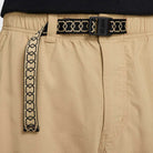 Close-up of the FV7347297 Kearny Cargo Pant Khaki by Nike SB, featuring an elastic waistband, a black and beige heart-patterned woven belt, and a black buckle labeled NIKE SB.
