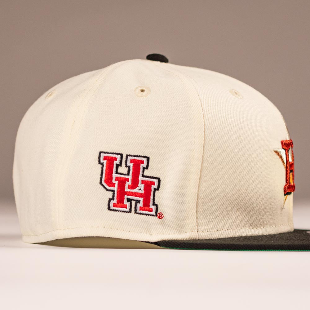 The Cougar 2.0 Houston Astros New Era Hat 5950 Fitted is cream-colored with a red and black UH logo on the side for the University of Houston, a dark green flat brim, and metal eyelets.