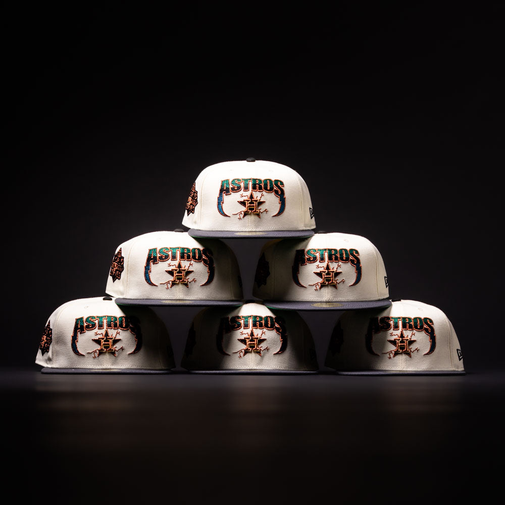 Six white Undaground 22WS Chrome Houston Astros New Era Hat 5950 Fitted hats are arranged in a pyramid shape against a dark background. These hats feature colorful embroidered logos and details as part of the Chrome Undaground collection.