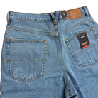 A close-up of the back of VN000C9VCDX1 Skate Check 5 Loose Shorts in stonewash blue denim, featuring two pockets, brown stitching, a brown leather Vans patch on the waistband, and a black Vans tag on one pocket.