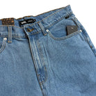 Close-up of VN000C9VCDX1 Skate Check 5 Loose Shorts in stonewash blue denim by Vans, showing coin pocket, zipper fly, button closure, belt loops, and visible brand label—classic heavyweight denim skate shorts built for lasting style.