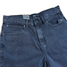 Close-up of VN000C9VEMQ1 Skate Check 5 Loose Shorts in washed black denim by Vans, featuring a button and zipper closure, front pockets, belt loops, and a visible inner waistband label—ideal for skateboarding or daily wear.