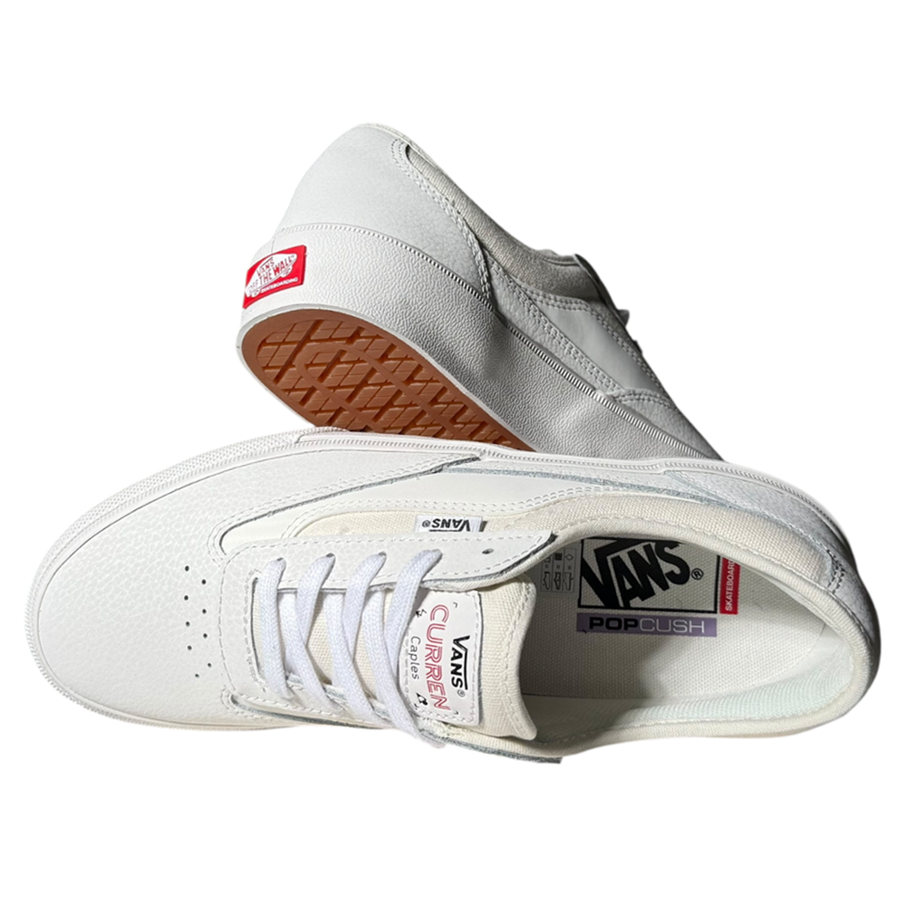 A pair of VN000D85JVY1 Skate Curren Caples Blanc de Blanc Vans shoes: one on its side showing the gum rubber sole, the other upright displaying the insole and tongue logos—classic vulcanized skate shoes for any skater.