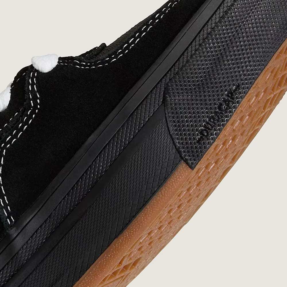Close-up of the VN000D9ZKOU Black Asphalt Suede Skate Wafflecup Half Cab Vans Shoes showing white stitching, white laces, a textured black Wafflecup midsole, and a brown gum rubber outsole with detailed design and textures.