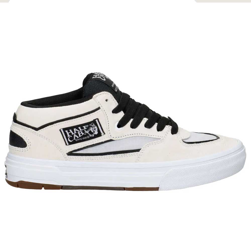The VN000D9ZYB2 White Black Suede Skate Wafflecup Half Cab Vans Shoes features a mid-cut design, black laces, black sole stripe, iconic Half Cab patch, textured white Wafflecup sole, and a brown bottom for grip and style.