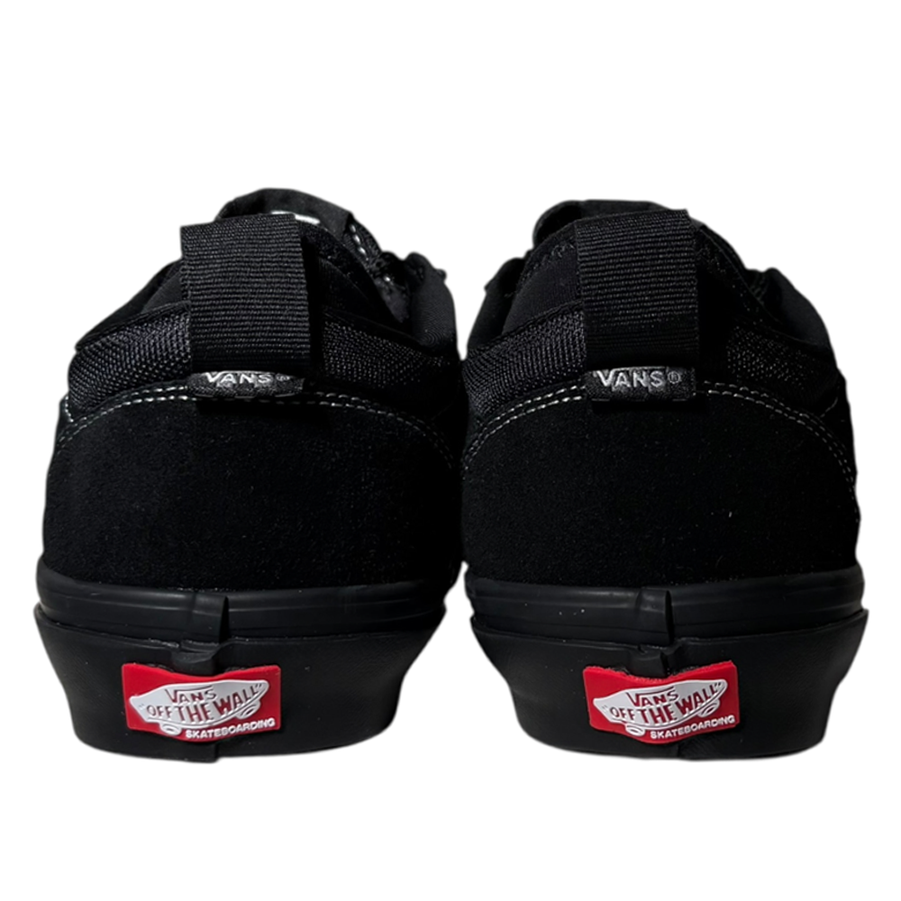 The image shows the back view of VN000EEHBKA1 Skate Safe Low Black Vans Skate Suede Rubber Shoes, featuring white stitching and the red Vans Off the Wall heel logo, known for their grip and durability for skateboarders.