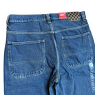 The VN000KXMAHU Skate Check 5 Loose Vintage Indigo Denim Vans Pant is shown from the back with two large square pockets, belt loops, a red label, and a black-and-gray checkerboard tag. Made from heavyweight denim for durability.