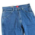 The VN000KXMAHU Skate Check 5 Loose Vintage Indigo Denim Vans Pant features heavyweight blue denim, a zipper fly, front pockets, belt loops, and a red waistband label. The pants are displayed flat on a white background.