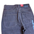 A close-up of the back of the VN000KXMY7U Skate Check 5 Loose After Dark Denim Vans Pant shows two rear pockets, a red waistband tag, a checkerboard patch beside it, and blue patterned detailing along one side.