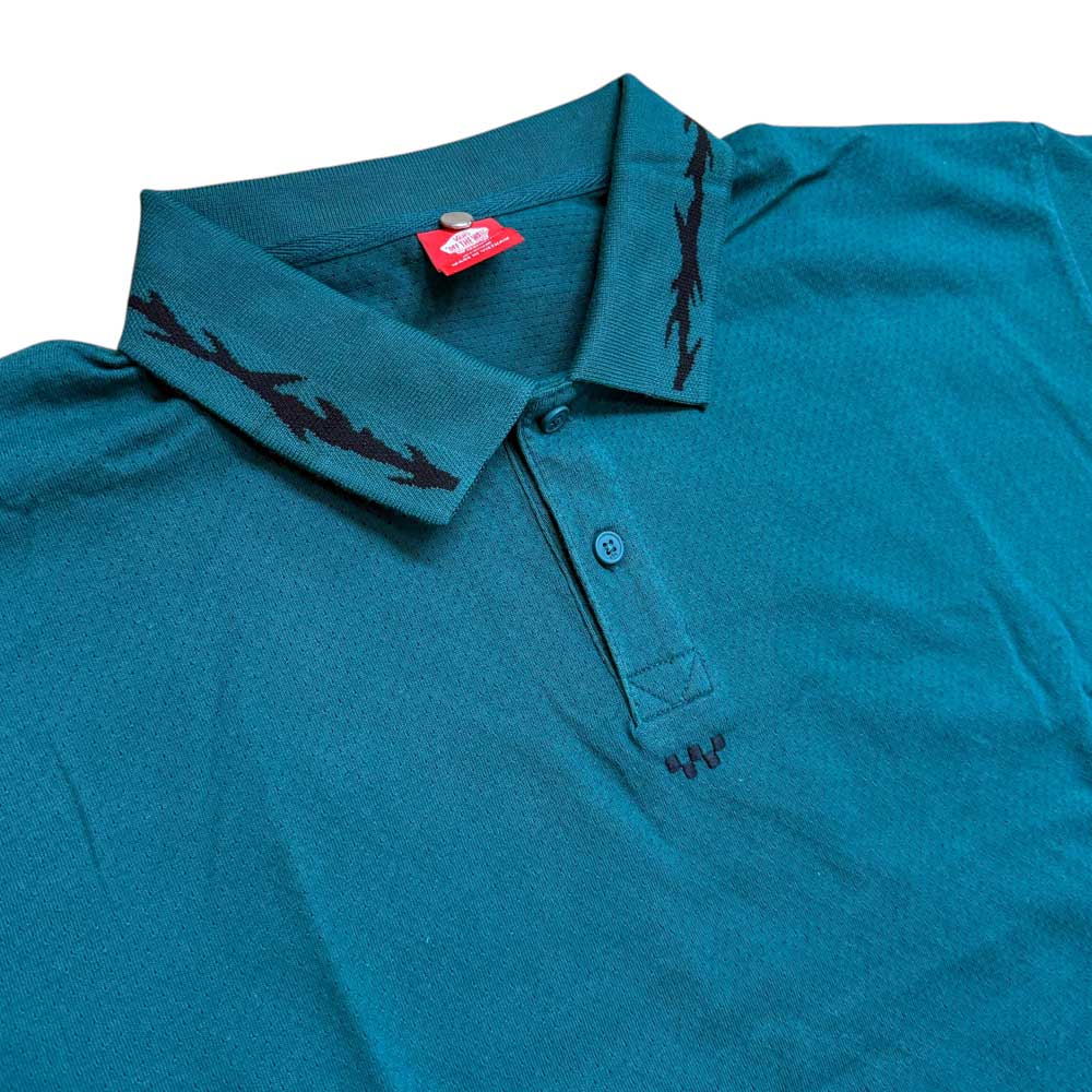 The VN000KYUCI21 Rain Forest Skate Mesh Polo by Vans in teal features a black zigzag collar, two buttons, and a small red tag near the neckline, shown laid flat on a white background.