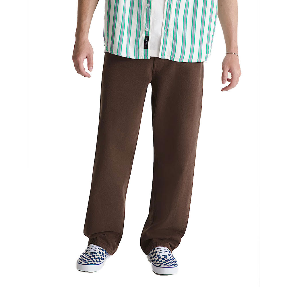 A person is wearing Vans Loose Denim Dark Brown VN000PH6DRB1 Skate Check 5 Pants, a green and white vertically striped shirt, and blue-and-white checkered slip-on shoes, shown from shoulders down against a white background.