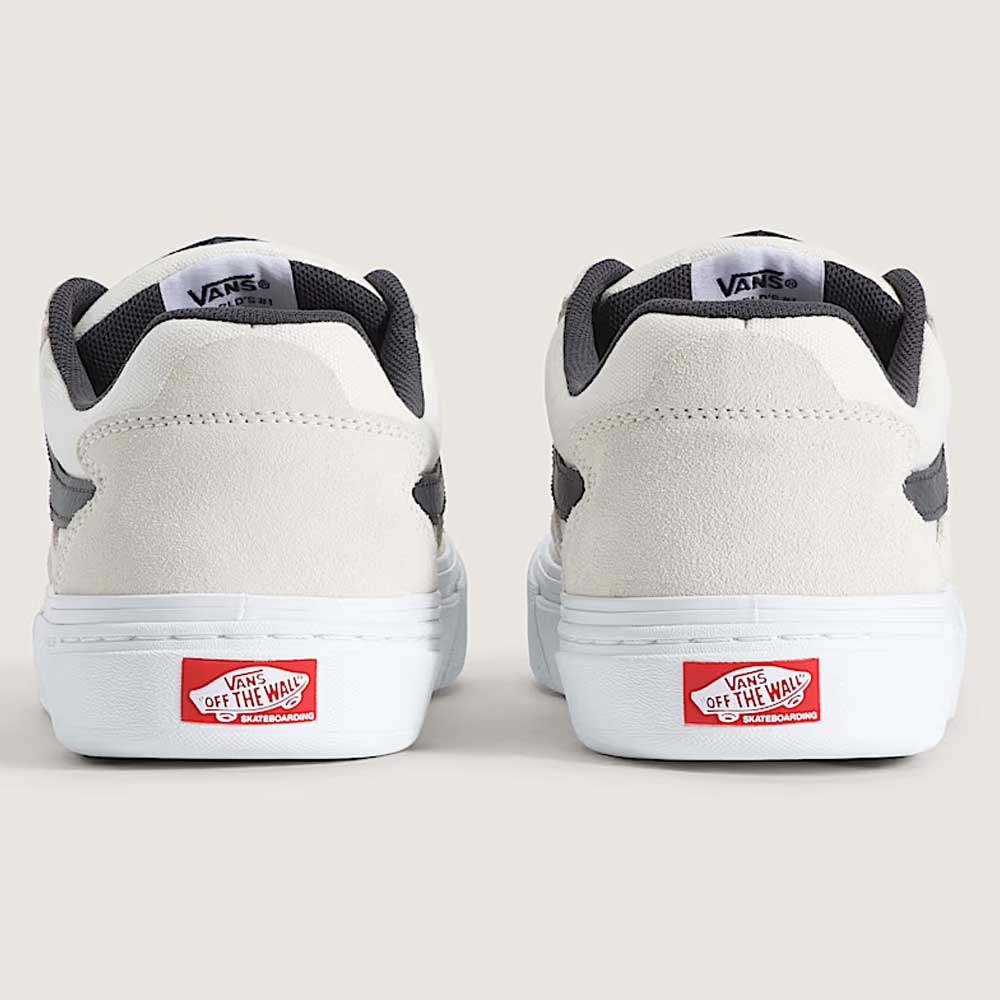Back view of two Vans Skate Kyle Walker Wafflecup White Gunmetal VN000DA4XQL1 suede and rubber shoes with gray accents, showcasing PopCush insoles and the iconic red Vans Off The Wall logo on the rubber heels, set against a beige background.