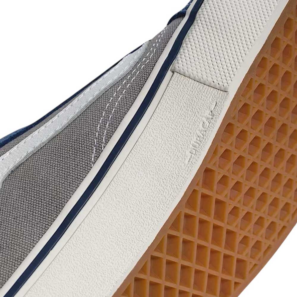 Close-up of the Vans Skate Old Skool Blue Gray VN000EDNY241 with gray and white upper, dark blue stripe, visible stitching, white textured rubber midsole, and brown waffle-patterned outsole.