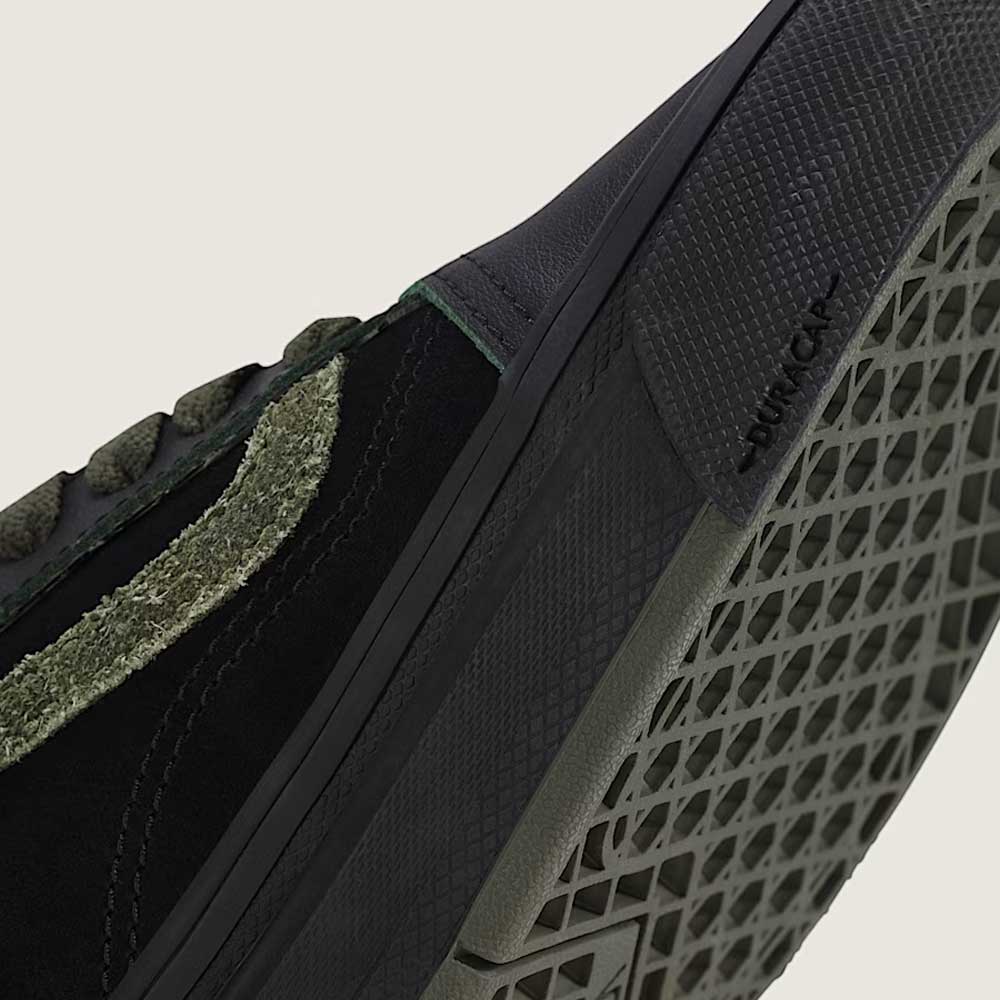 Close-up of Vans Skate Half Cab Walnut Gum VN0A5FCD77J1 suede skate shoes in black, featuring a green textured stripe, black patterned sole with “DURACAP” near the toe, and PopCush cushioning for skate impact protection.