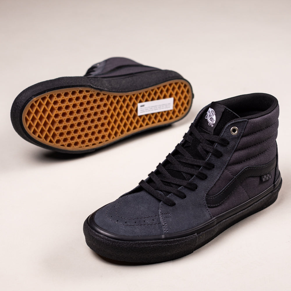 A pair of VN0A5FCCY011 Charcoal Black Skate SK8-HI Suede Vans Shoes with black laces and gum waffle soles. One high-top stands upright; the other lies on its side, displaying the iconic sole pattern.