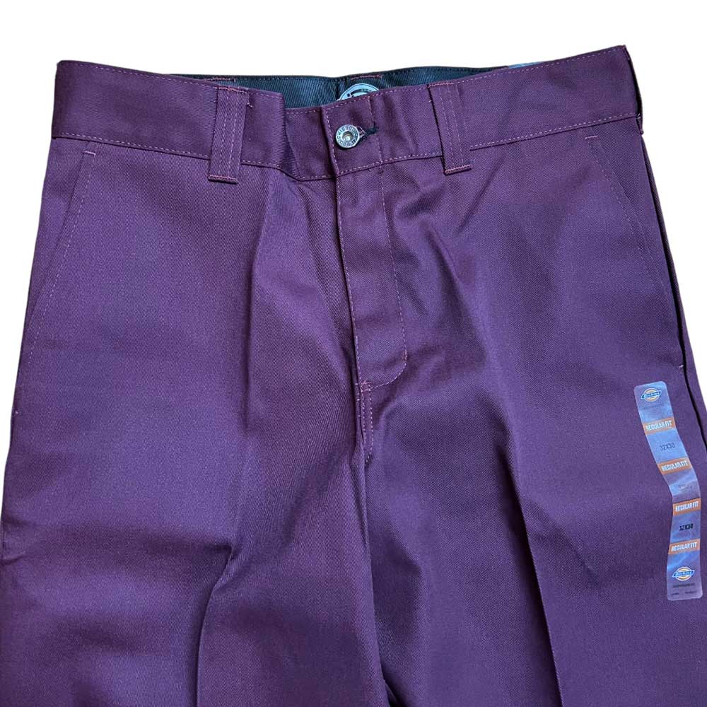 A close-up of the WPSK67MR Maroon Dickies Skateboarding Pant Regular Fit Twill, featuring belt loops, button and zipper closure, and a blue and orange waistband tag.