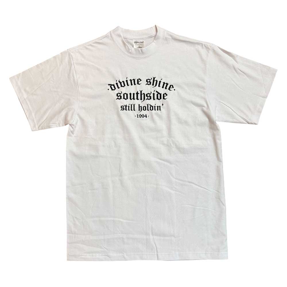 The White Divine Shine x Southside Still Holdin Max Heavyweight Tee features black gothic text on the chest and authentic streetwear style, inspired by Southside Skatepark. Embroidered design, laid flat on a white background.