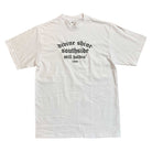 The White Divine Shine x Southside Still Holdin Max Heavyweight Tee features black gothic text on the chest and authentic streetwear style, inspired by Southside Skatepark. Embroidered design, laid flat on a white background.