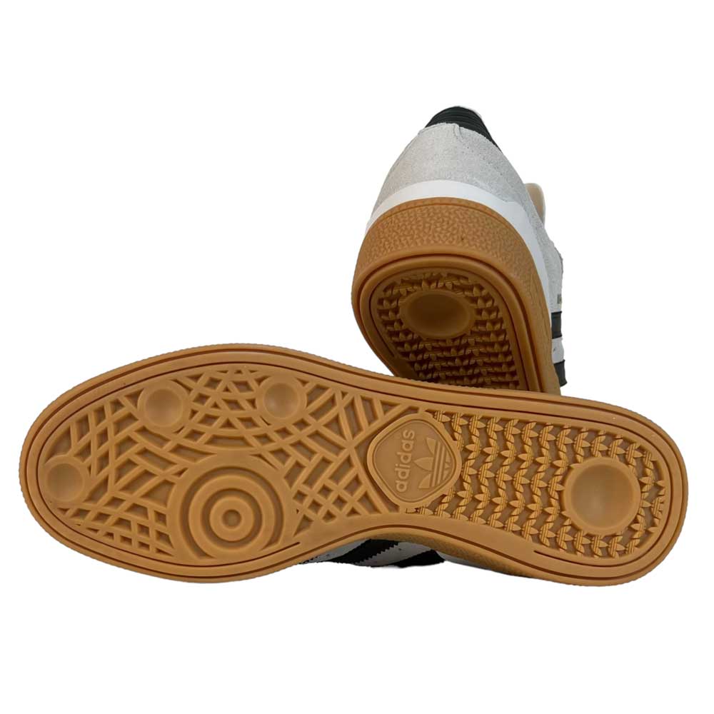 A pair of White Grey Shaoli Gum Busenitz Adidas Skateboarding Suede Shoes: one stands upright, the other sole-up to display the textured Shaoli Gum sole with Adidas logo; white uppers and black stripes add classic skate style.