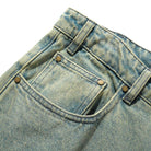 Close-up of the front pocket area of Wide Cut Tinted Blue Wash Denim Jeans by Butter Goods, featuring a small coin pocket inside the main pocket, metal rivets, and belt loops.