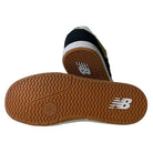 A pair of YOUTH YS425 BNT Black White Tan New Balance Numeric Suede Skateboarding Shoes are shown—one flat to display its tan, textured sole with a white NB logo, the other upright highlighting the heel and part of the suede upper.