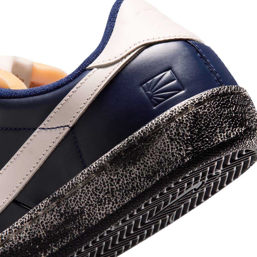 Close-up of the heel of a blue void and sail Zoom Tennis Classic x Rassvet IO9846400 Nike SB leather skateboarding shoe, featuring a textured, slightly worn black-and-white sole and an embossed geometric logo near the heel.