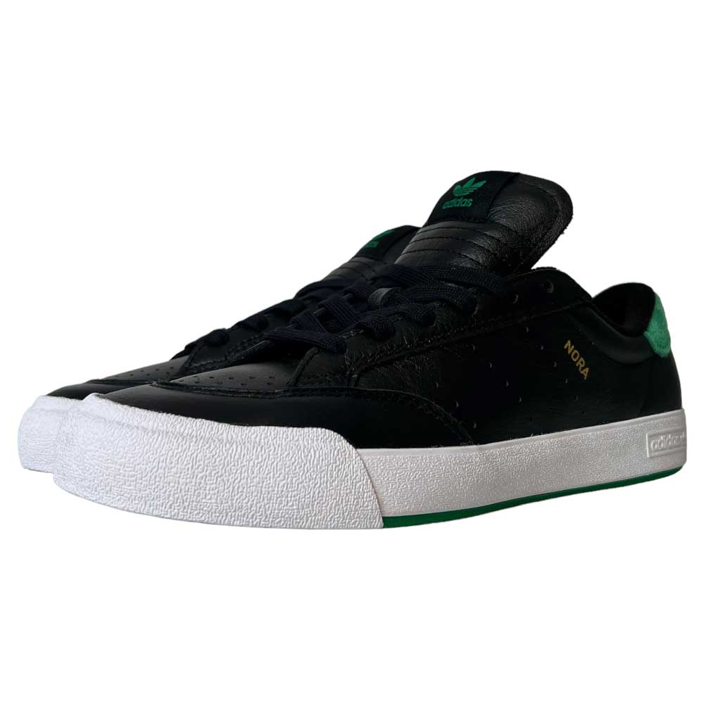 A pair of Adidas Nora Black Green White Leather Shoes with green accents, a white textured rubber toe cap and sole, and "NORA" in gold on the side. Vintage-inspired skate shoes are side by side, facing left.