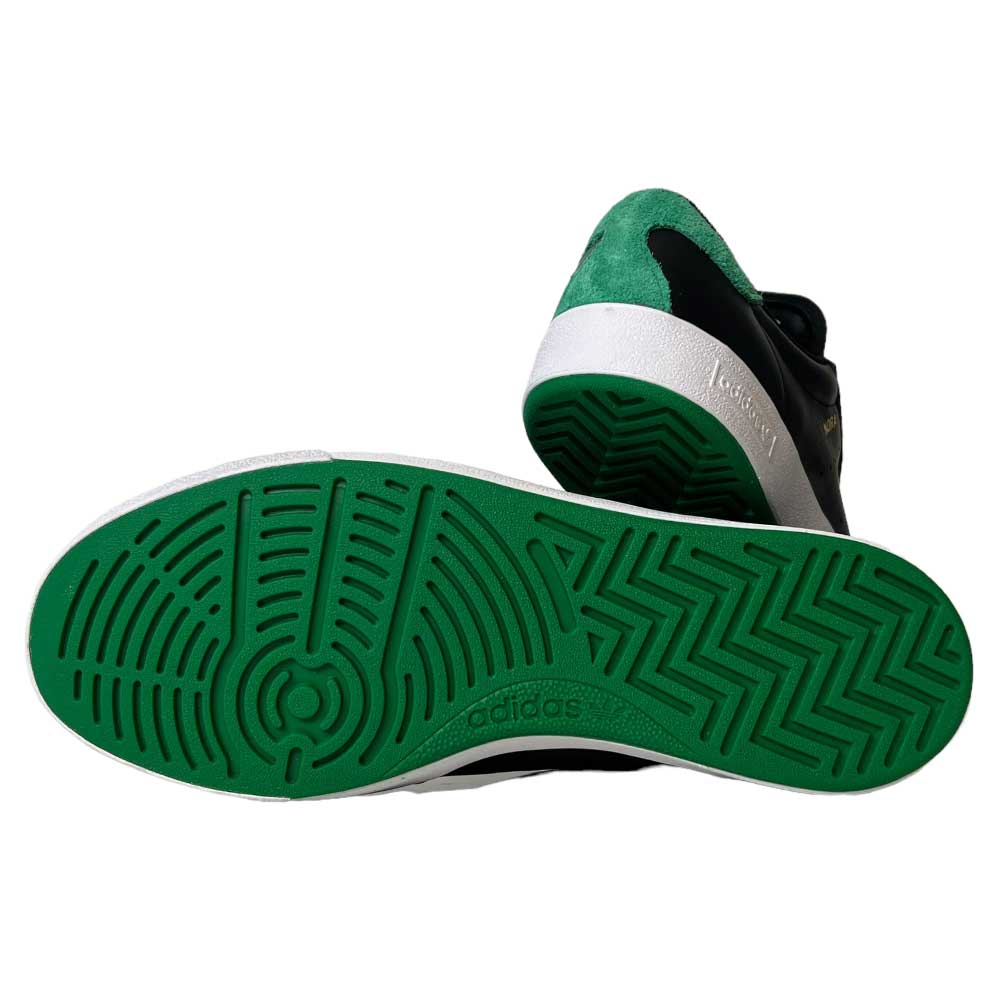 A pair of Adidas Nora Black Green White Leather Shoes—one highlights the textured green rubber sole, while the other showcases the retro skate-inspired design with a green suede heel and black upper.