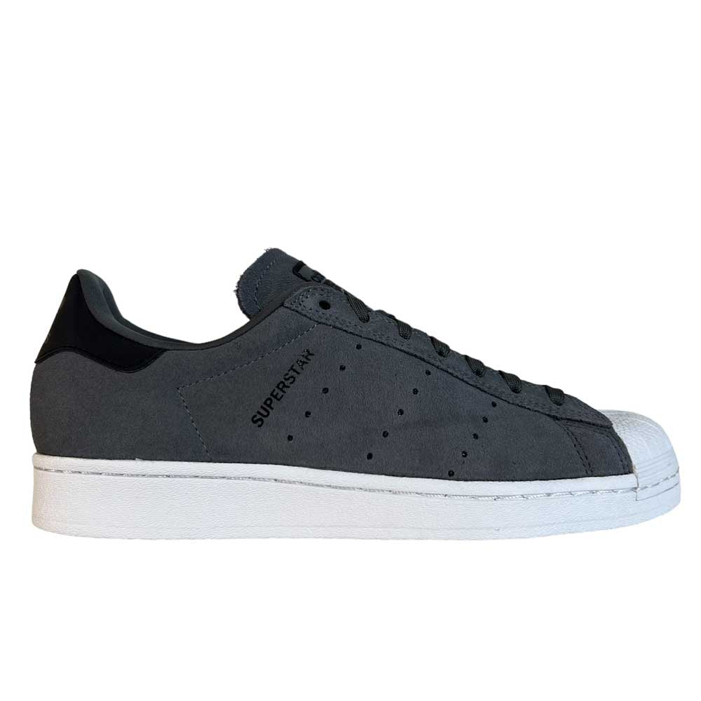 The Superstar ADV Adidas Grey Black Suede Shoes feature reflective badging, a white sole, perforated stripes, and the signature white shell toe, with "SUPERSTAR" printed on the side for a bold skateboarding style.