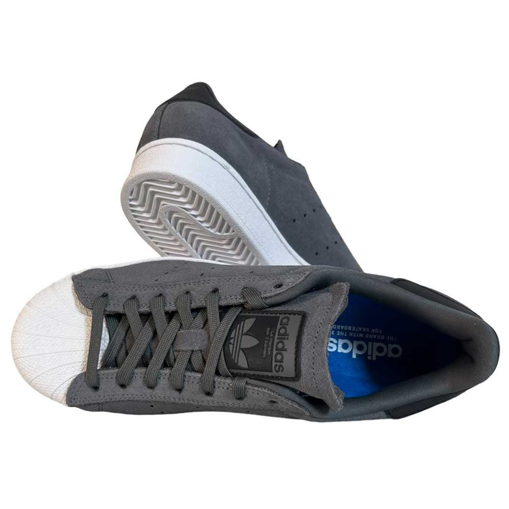 A pair of Superstar ADV Adidas Grey Black Suede Shoes with white rubber shell toes, white soles, reflective badging, and the Adidas logo on the tongue; one shoe is upright, the other is on its side displaying the sole.