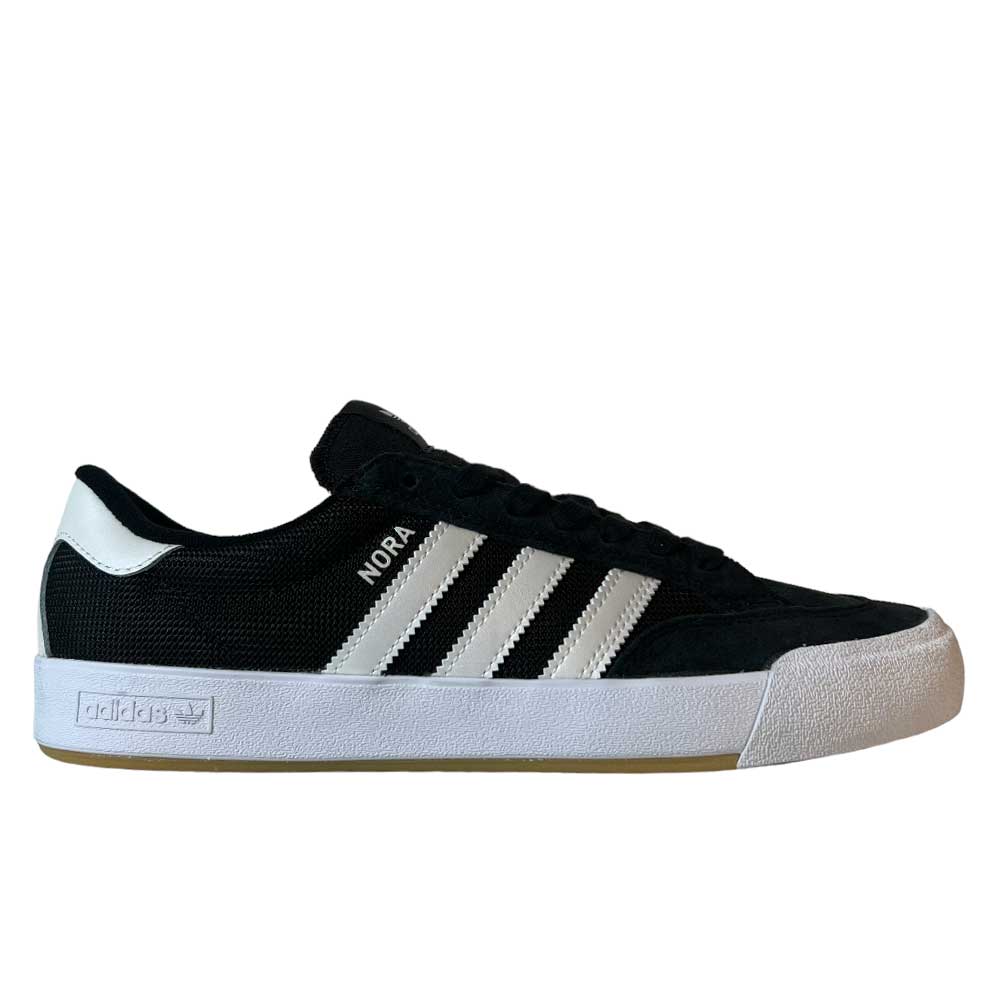 The Adidas Nora Black Zero Spark Suede Knit Shoes are vintage-inspired black skate shoes with white stripes, NORA branding for Nora Vasconcellos, a white heel tab, and a thick white sole with a gum bottom.