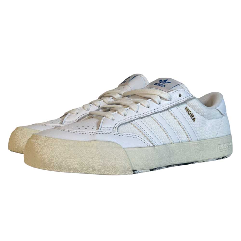 These vintage-inspired Adidas Skateboarding Nora White White Leather Knit Shoes feature cream rubber soles, a blue Adidas tongue logo, and gold NEGR lettering—created in collaboration with Nora Vasconcellos for a timeless low-top style.