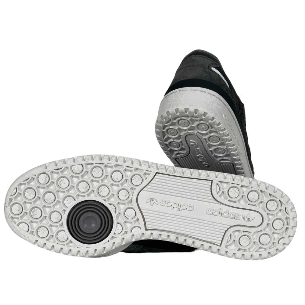 Two black Forum 84 Low Adidas Skateboarding Carbon White Gray Leather Shoes are shown with white soles displaying circular grips, the Adidas logo, and a black circular detail on one heel.