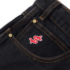 Close-up of the Logo Baggy Denim Jeans Washed Black Cash Only, showing an oversized pocket with orange stitching, brass rivets, and a bold red and white embroidered dollar sign for a standout cash only look.