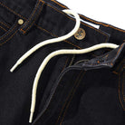 Close-up of Logo Baggy Denim Jeans Washed Black Cash Only, featuring orange stitching, a brass waist button, and a white drawstring at the waistband. The fly is partially open.