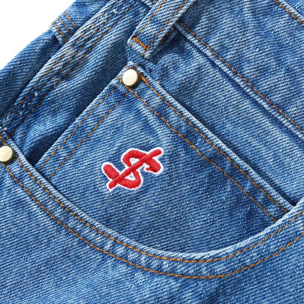 Close-up of Logo Baggy Denim Shorts Washed Indigo Cash Only, showing a blue front pocket with orange stitching and a red embroidered dollar sign overlapping an S—ideal for a cash only vibe.