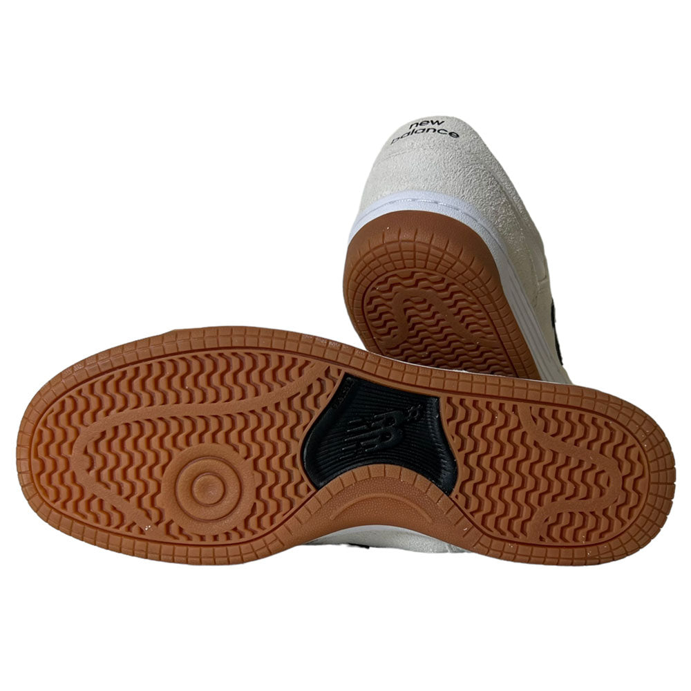 A pair of 480 SWG New Balance Numeric Shoes in suede white and black, featuring a brown rubber sole with visible tread pattern and central Numeric logo—ideal for those seeking stylish, durable skate footwear.