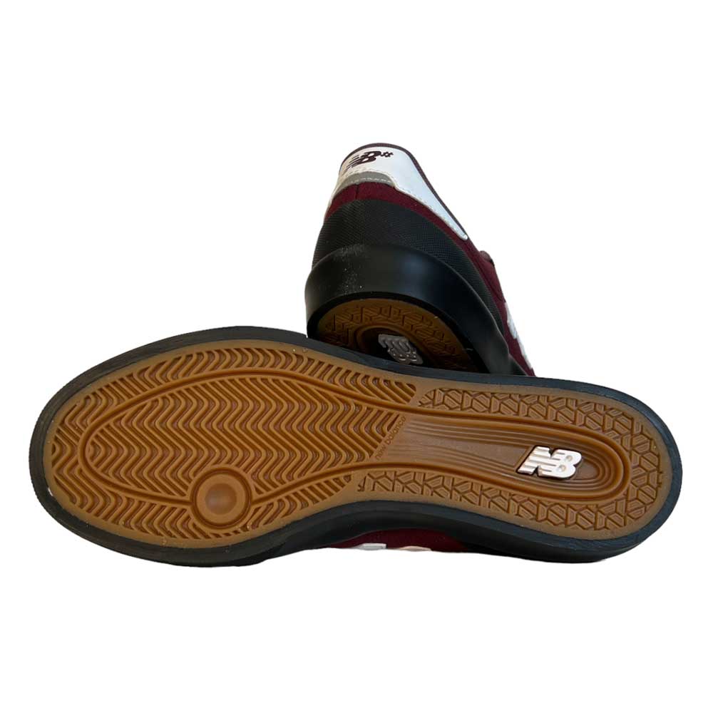 A pair of 272 BNB New Balance Numeric suede shoes in maroon and white, with one upright and one on its side showing the brown vulcanized sole’s textured pattern and the New Balance logo.