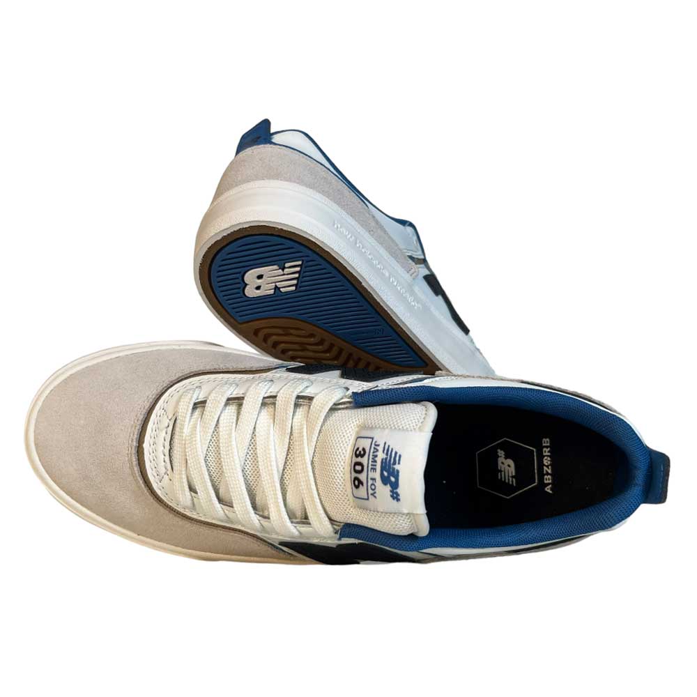A pair of 306 TWC Jamie Foy New Balance Numeric suede shoes in white with blue, black, and brown accents. One shoe is shown top-down, the other on its side displaying the sole and classic New Balance logo.